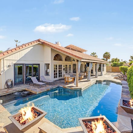 Covered patio with outdoor dining and pool at dusk